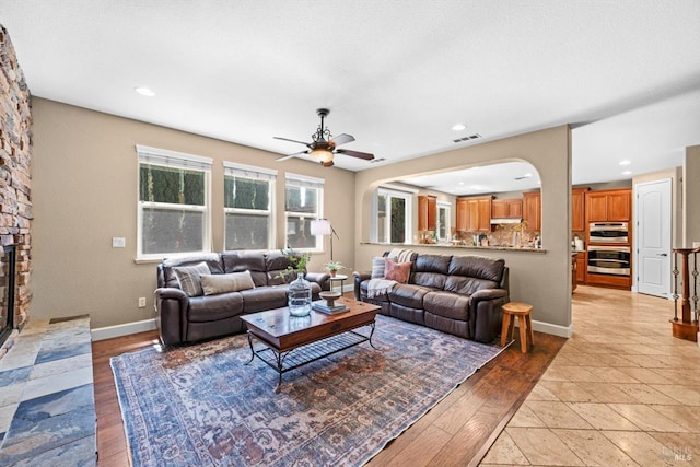 living room with ceiling fan, a fireplace, recessed lighting, baseboards, and visible vents