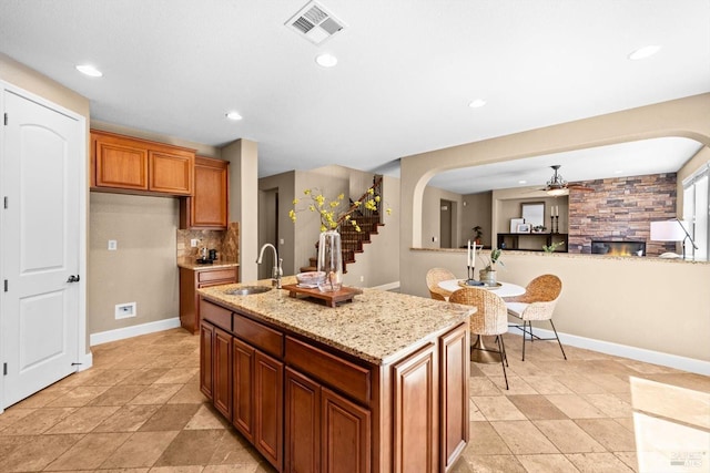 kitchen featuring a sink, baseboards, ceiling fan, and visible vents