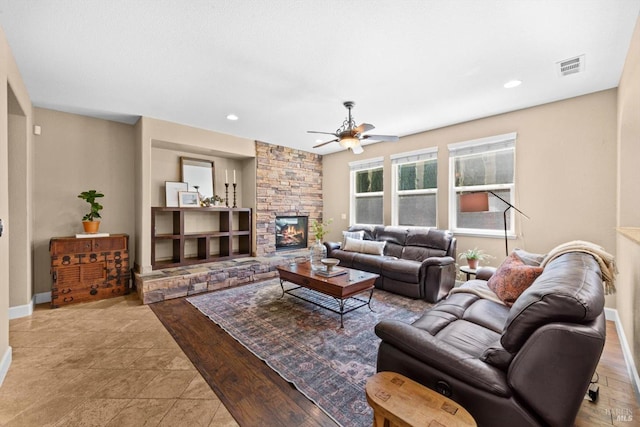 living room with a ceiling fan, a stone fireplace, visible vents, baseboards, and recessed lighting