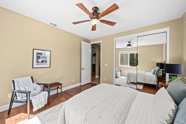 bedroom with visible vents, a closet, wood finished floors, baseboards, and ceiling fan