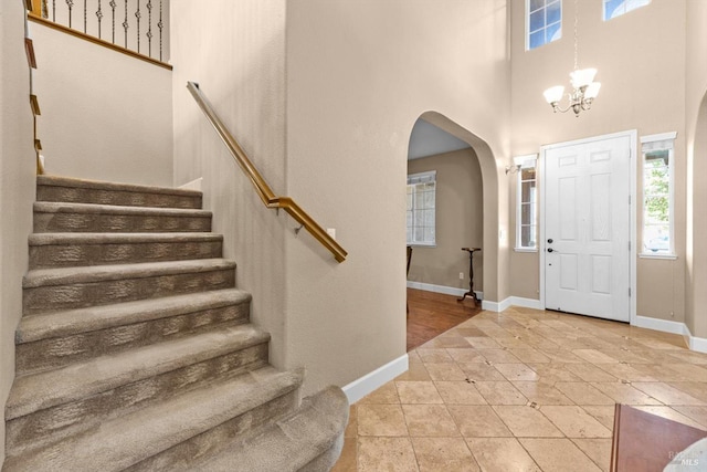 entrance foyer with an inviting chandelier, arched walkways, and a towering ceiling