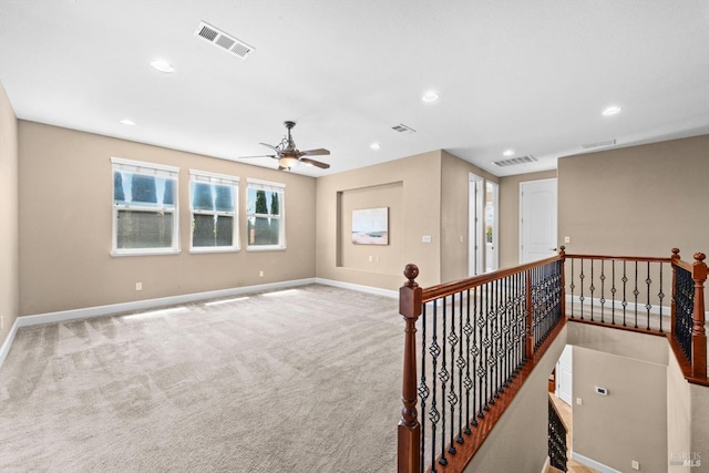 carpeted spare room with baseboards, visible vents, and ceiling fan