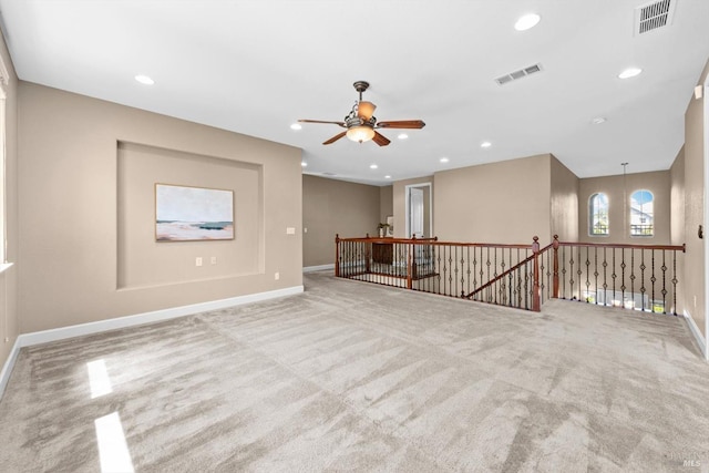 carpeted spare room with visible vents, a ceiling fan, and baseboards