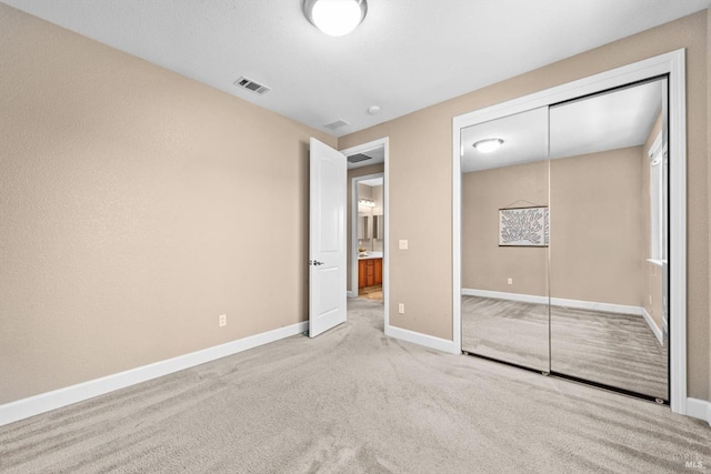 unfurnished bedroom featuring carpet floors, baseboards, a closet, and visible vents