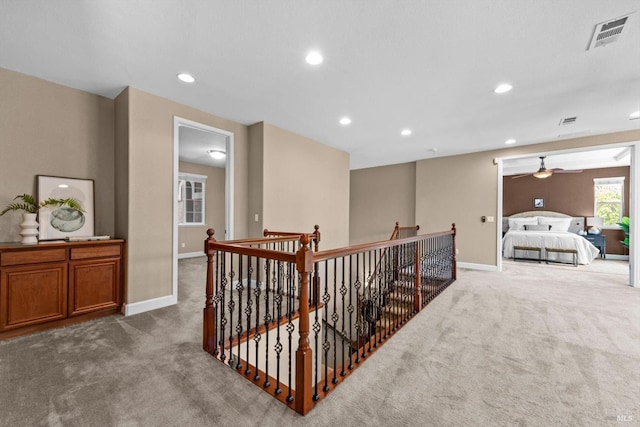 hall with visible vents, baseboards, an upstairs landing, and carpet