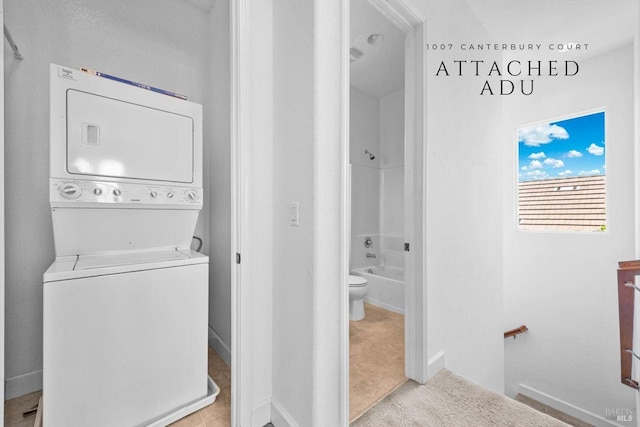 laundry room with baseboards, stacked washer and clothes dryer, and laundry area