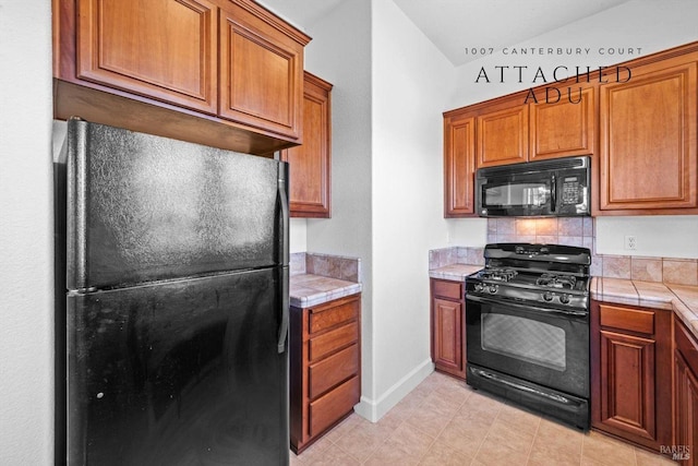 kitchen with tile counters, brown cabinetry, black appliances, and tasteful backsplash