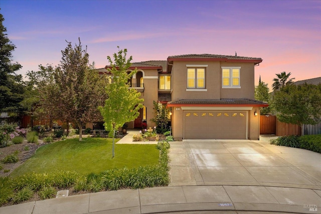 traditional home featuring fence, an attached garage, a tile roof, a front yard, and driveway
