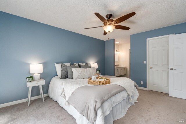 bedroom with carpet floors, a textured ceiling, a ceiling fan, baseboards, and ensuite bathroom