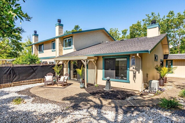 rear view of property with a chimney, central air condition unit, fence, a patio, and a shingled roof