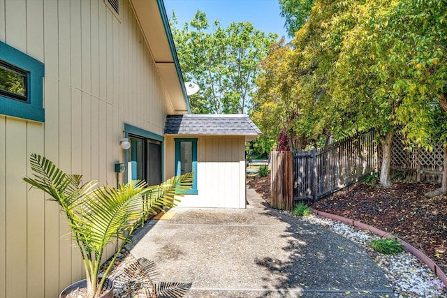 view of side of property featuring fence and roof with shingles