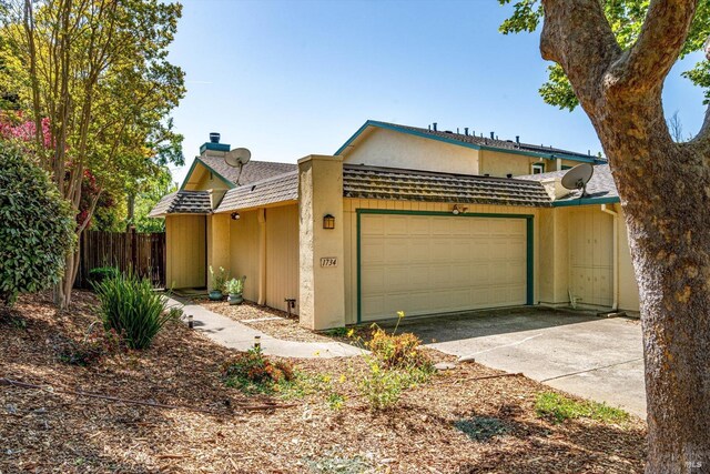 multi unit property with a garage, fence, and concrete driveway