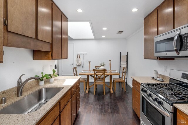 kitchen featuring visible vents, crown molding, a sink, stainless steel appliances, and dark wood-type flooring