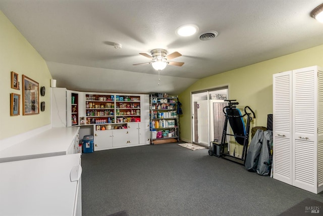 interior space with ceiling fan, visible vents, lofted ceiling, and dark colored carpet