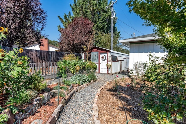 view of yard featuring an outdoor structure, fence, and a storage unit