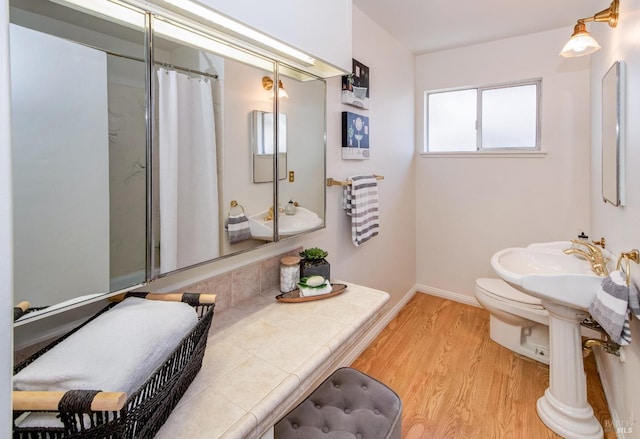 full bath featuring a sink, toilet, baseboards, wood finished floors, and a shower with curtain