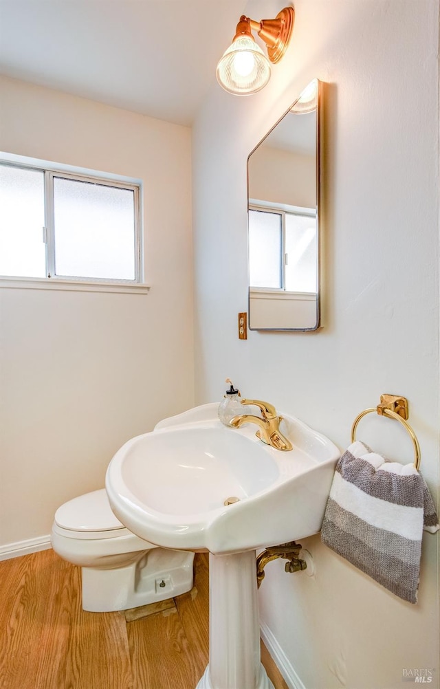 bathroom with plenty of natural light, baseboards, wood finished floors, and toilet