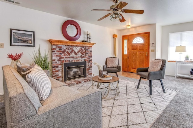 living room featuring carpet floors, ceiling fan, a brick fireplace, and visible vents