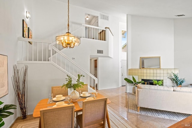 dining area with stairs, visible vents, an inviting chandelier, and a towering ceiling