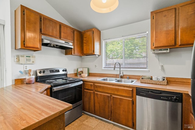 kitchen featuring a sink, brown cabinetry, stainless steel appliances, under cabinet range hood, and vaulted ceiling