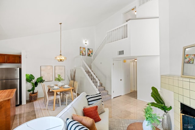 living area featuring visible vents, baseboards, high vaulted ceiling, and stairway