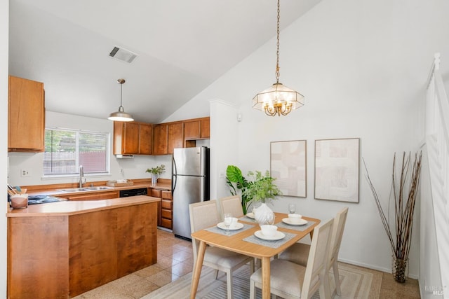 kitchen featuring brown cabinets, a sink, freestanding refrigerator, a peninsula, and visible vents
