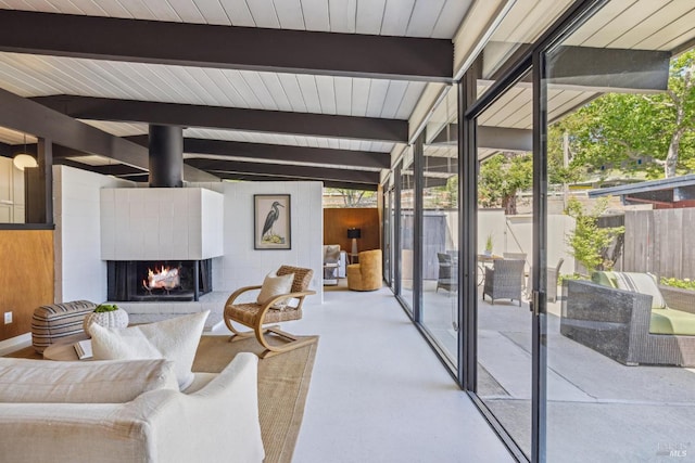 living room with beam ceiling, a lit fireplace, plenty of natural light, floor to ceiling windows, and wood ceiling