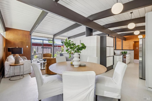 dining space featuring wood walls and beamed ceiling