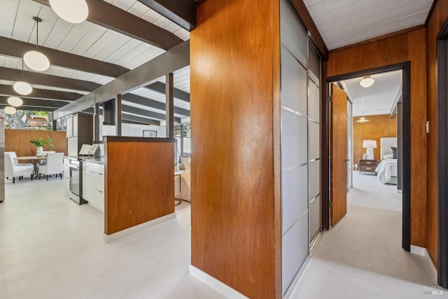 hallway with wood walls, beam ceiling, and wood ceiling