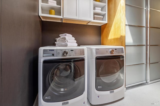 washroom featuring cabinet space and washer and clothes dryer