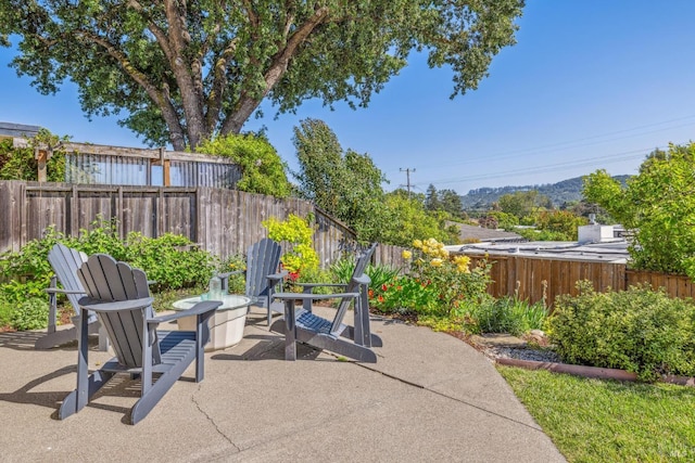 view of patio / terrace with an outdoor fire pit, a fenced backyard, and a mountain view