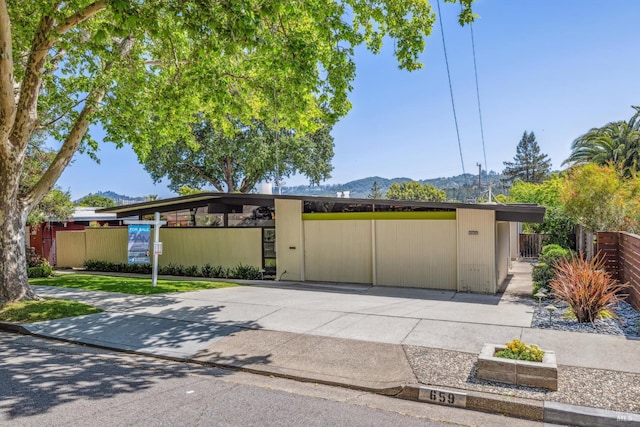 mid-century home featuring a mountain view and fence
