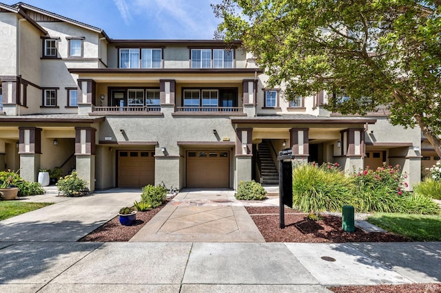 multi unit property featuring a garage, stucco siding, concrete driveway, and stairway