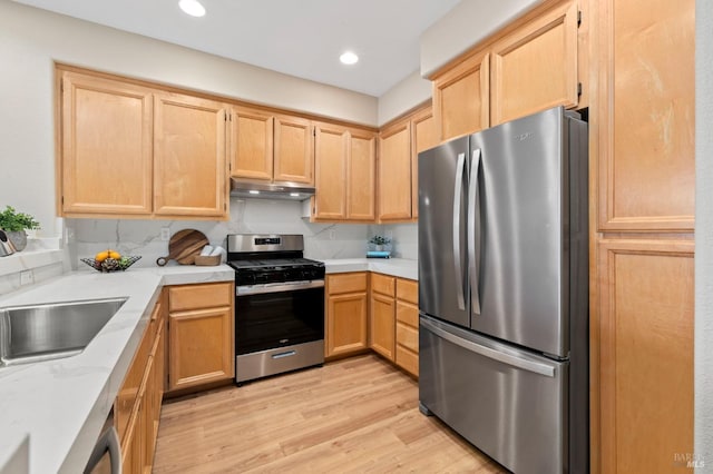 kitchen with light brown cabinetry, appliances with stainless steel finishes, light wood-style floors, and under cabinet range hood