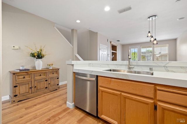 kitchen featuring visible vents, stainless steel dishwasher, a sink, light countertops, and light wood-style floors