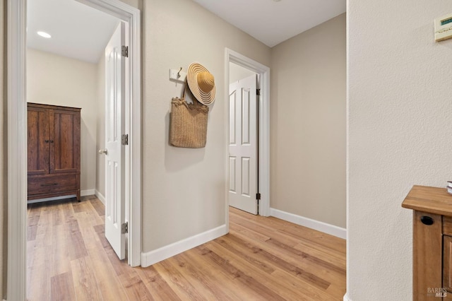 corridor with light wood-style floors and baseboards