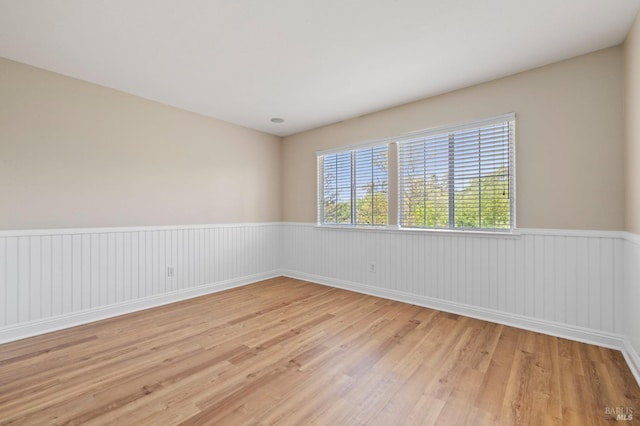 spare room featuring light wood-style floors and a wainscoted wall