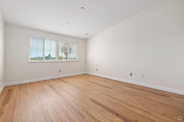 spare room featuring baseboards and light wood-style floors