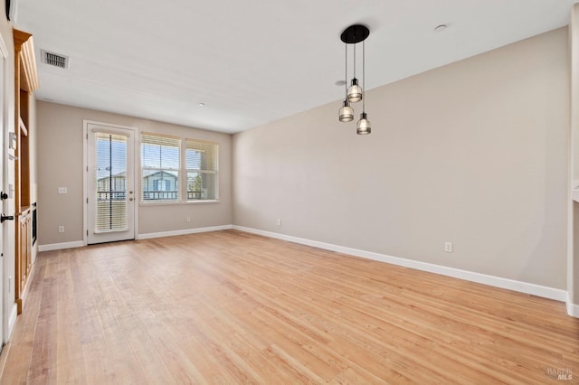 unfurnished room featuring visible vents, light wood finished floors, and baseboards
