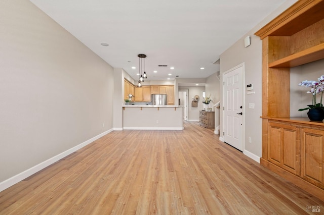 unfurnished living room with recessed lighting, baseboards, and light wood finished floors