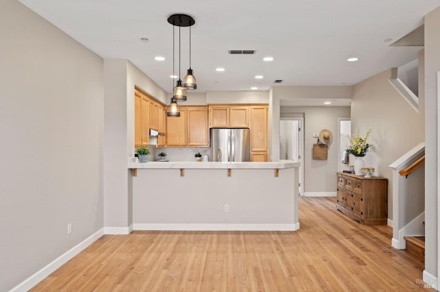 kitchen featuring light brown cabinetry, freestanding refrigerator, a peninsula, light wood-type flooring, and visible vents