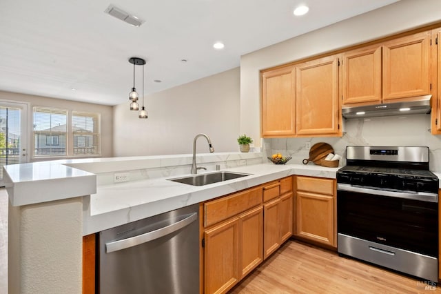kitchen with visible vents, a peninsula, under cabinet range hood, a sink, and stainless steel appliances