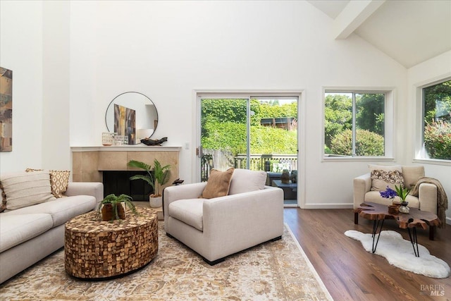 living area featuring a fireplace, beam ceiling, wood finished floors, high vaulted ceiling, and baseboards