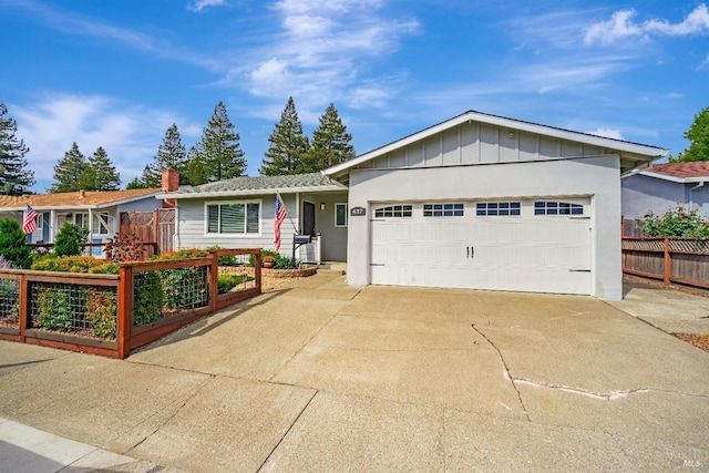 single story home with fence, an attached garage, board and batten siding, a vegetable garden, and concrete driveway