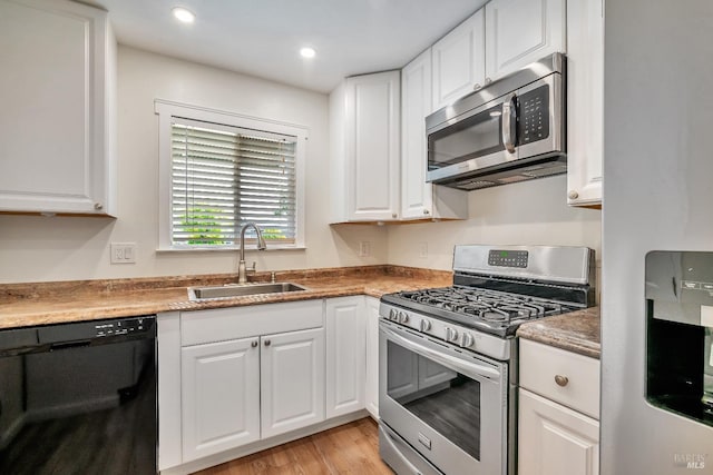 kitchen with stainless steel appliances, white cabinetry, and a sink