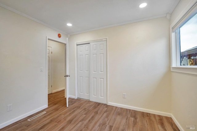unfurnished bedroom with visible vents, light wood-style flooring, crown molding, and baseboards