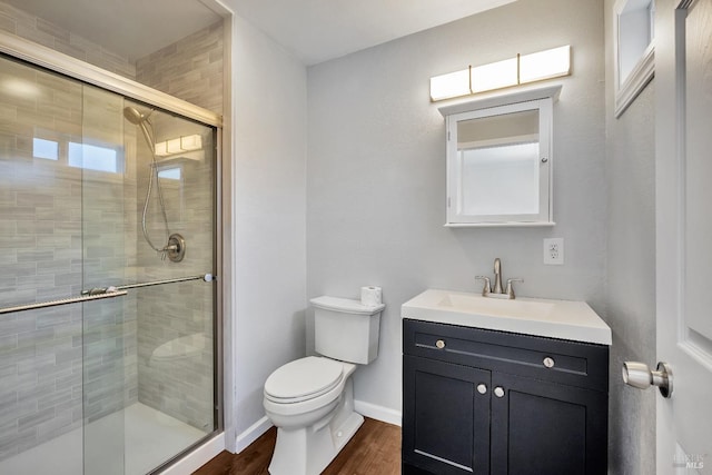 bathroom with vanity, toilet, baseboards, wood finished floors, and a stall shower