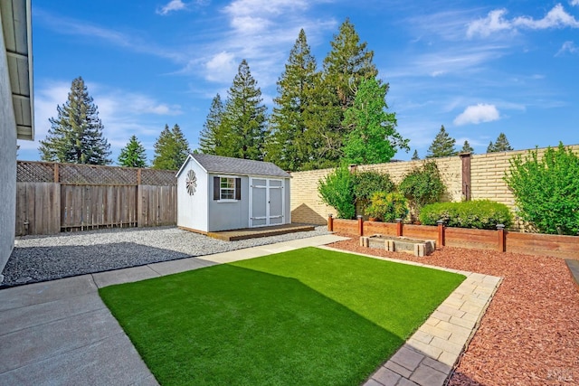 view of yard with a garden, a storage shed, an outbuilding, a fenced backyard, and a patio