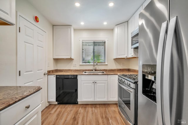 kitchen featuring light wood-type flooring, a sink, white cabinets, stainless steel appliances, and recessed lighting