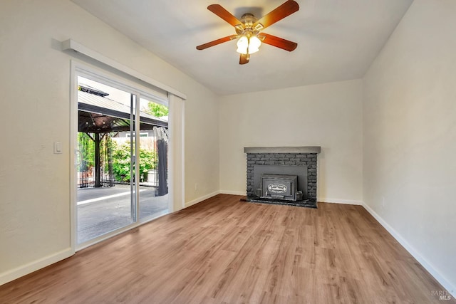 unfurnished living room featuring baseboards, ceiling fan, wood finished floors, and a fireplace